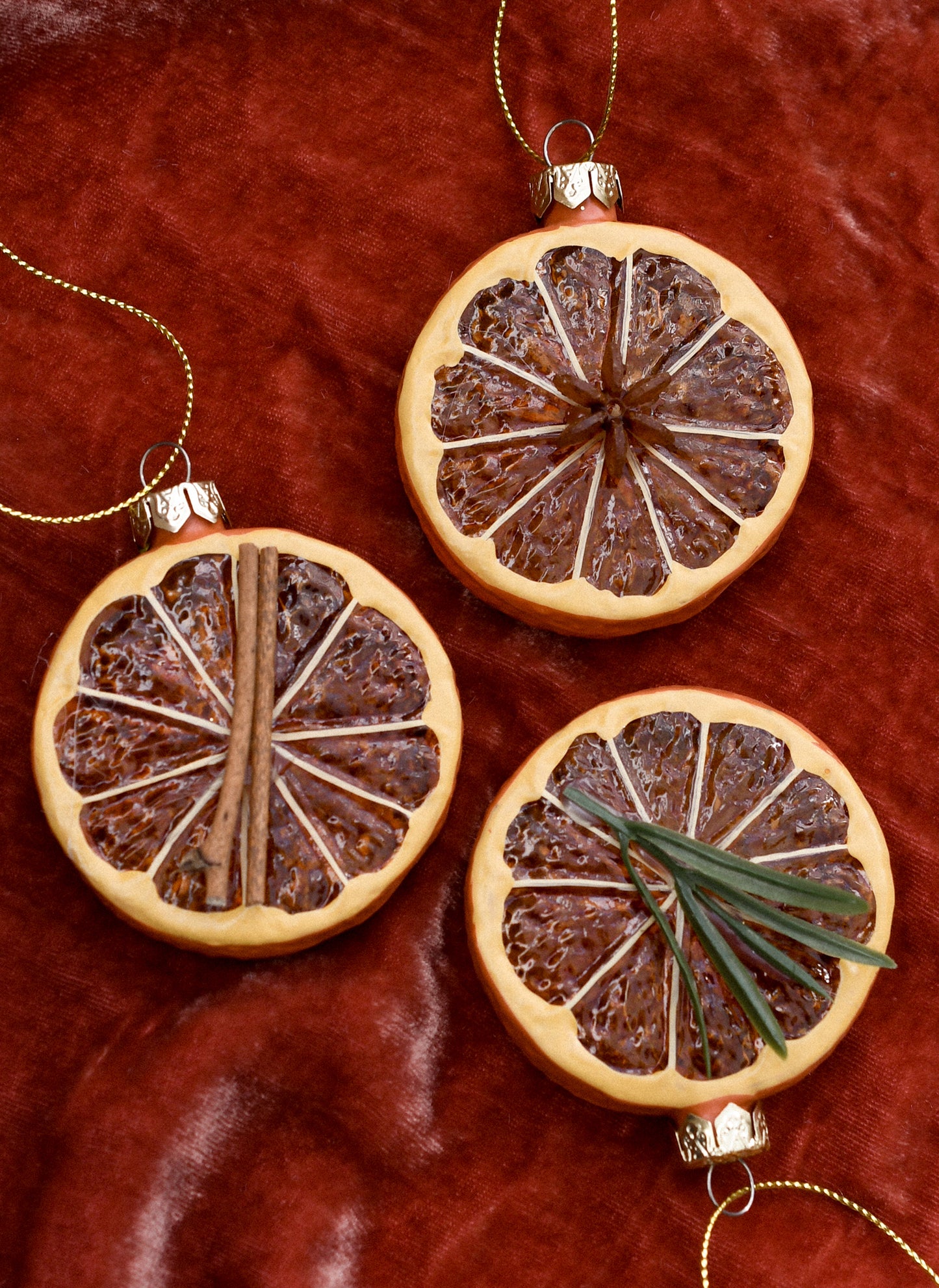 Glass ornaments of orange slices decorated with rosemary, cinnamon and star anise.
