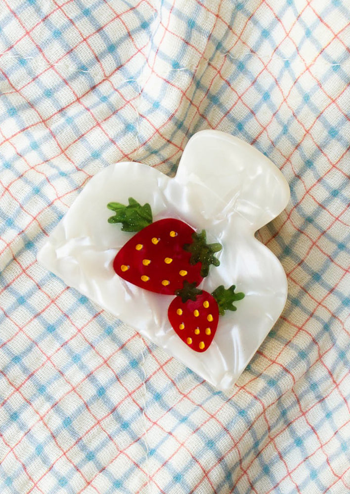 1: A pearl white hair clip with red strawberry.