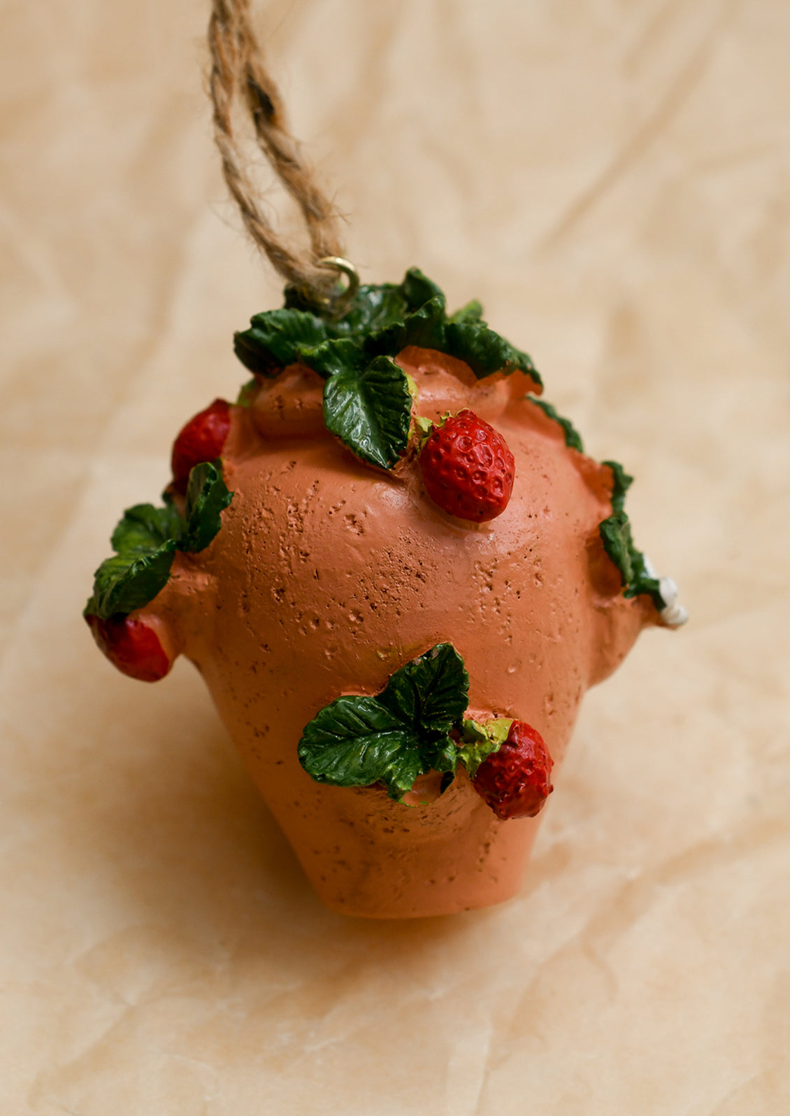 A holiday ornament depicting a terracotta strawberry planter with strawberries.