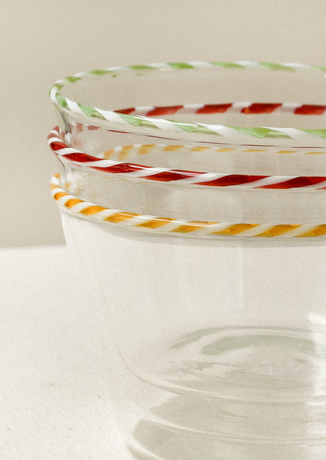 A stack of clear glass bowls with colorful striped rims