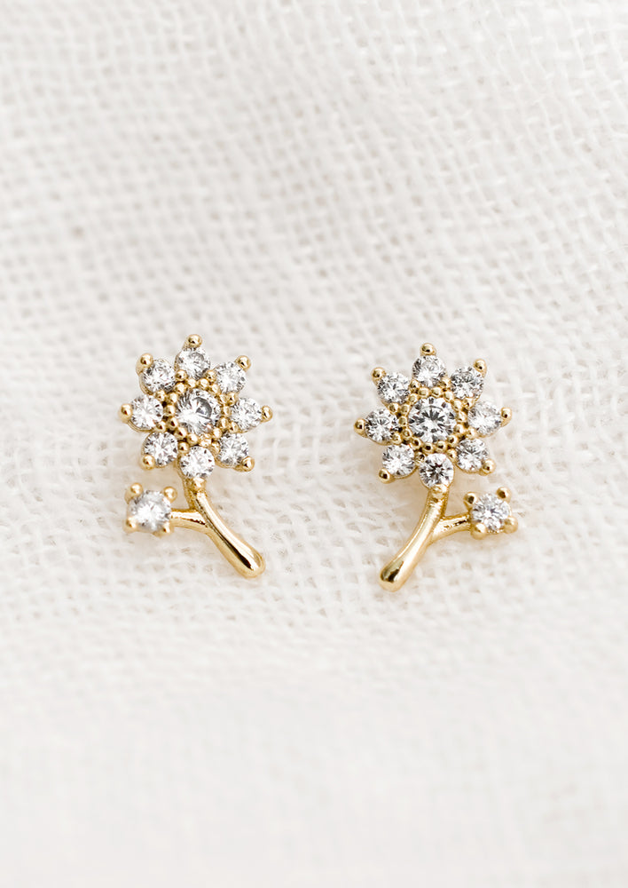 1: A pair of small gold studs in shape of clear crystal studded flower with stem.