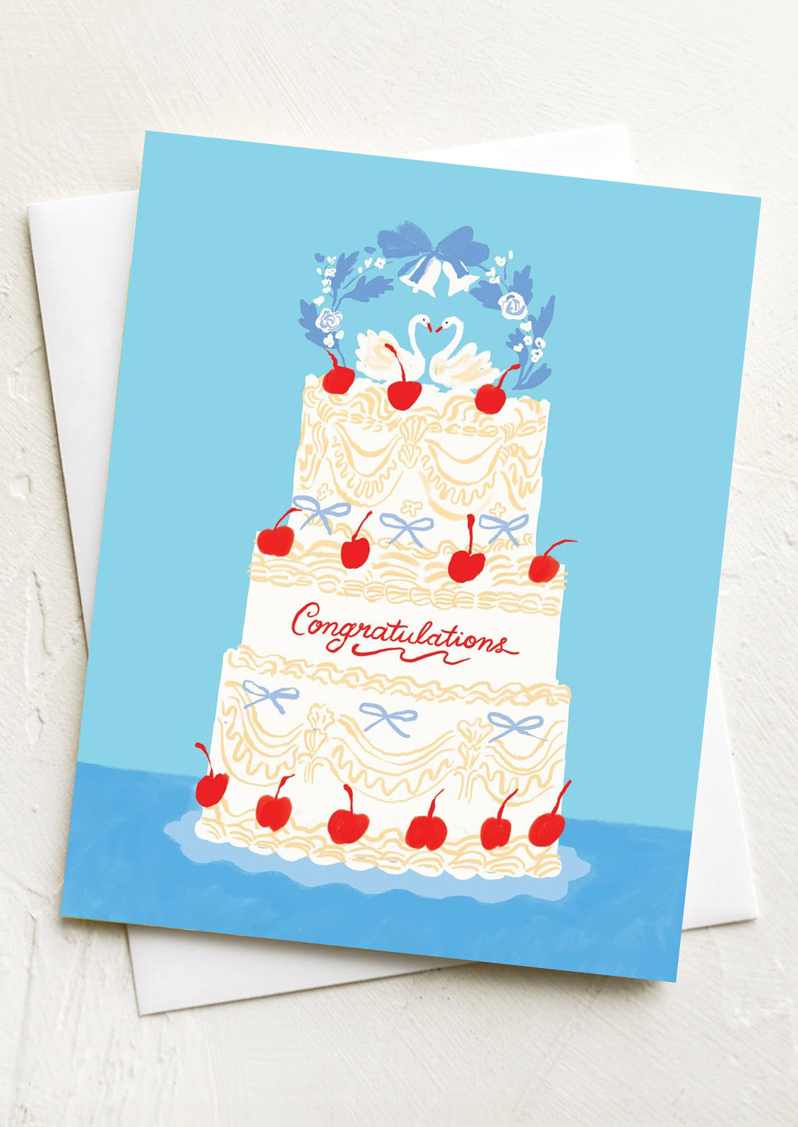 A greeting card with illustration of wedding cake with swans at top, text reads "Congratulations".
