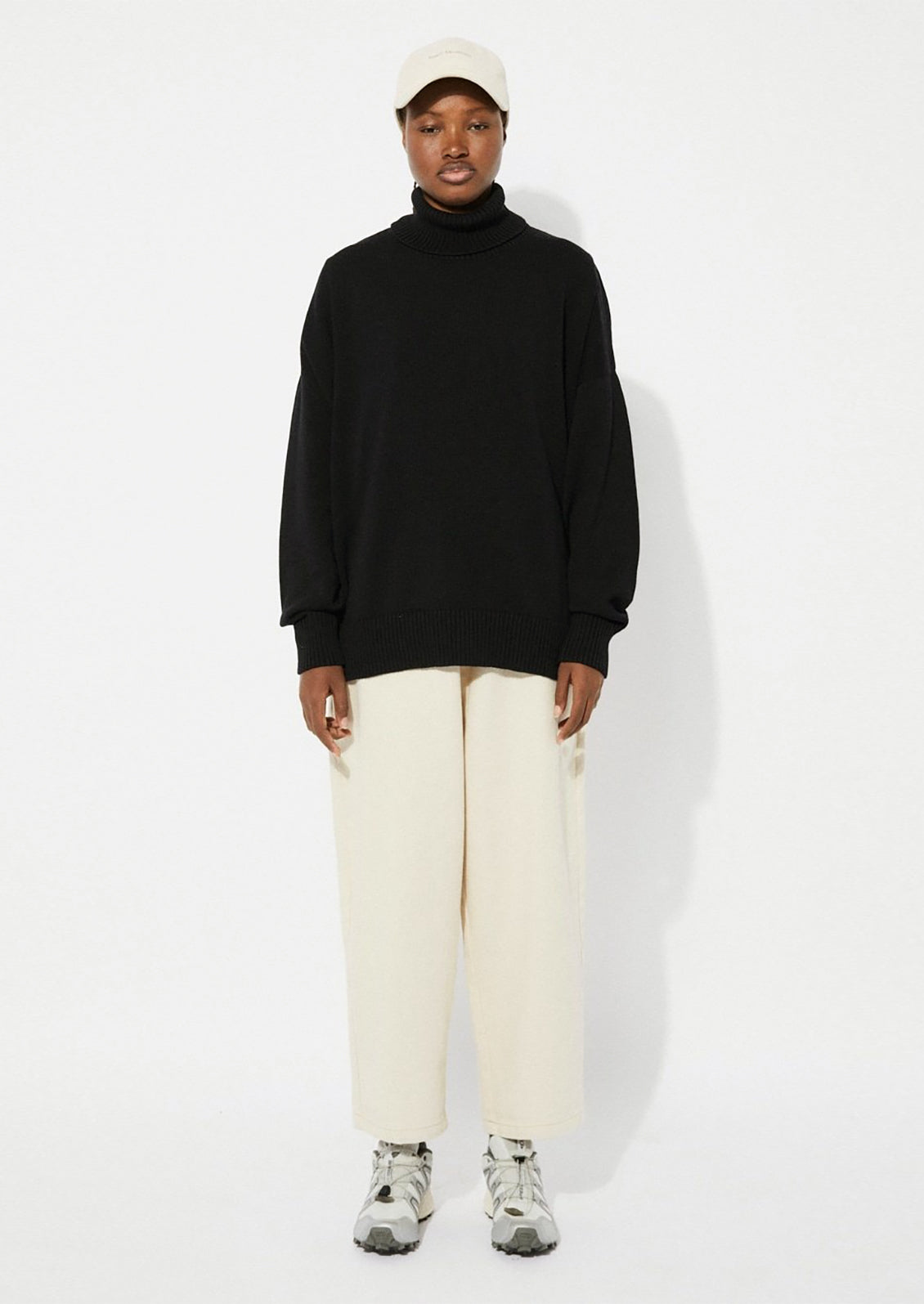 A woman wearing an oversized turtleneck sweater in black.