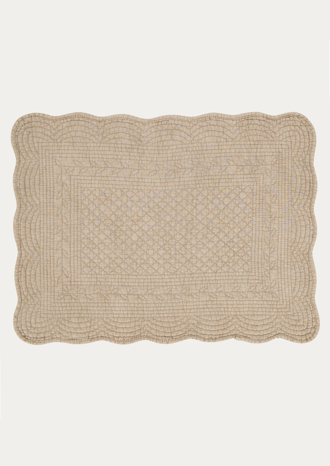 A quilted cotton placemat with scalloped edges, in taupe color.