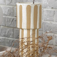 2: A tall sculptural vase with sandy and white vertical stripes.