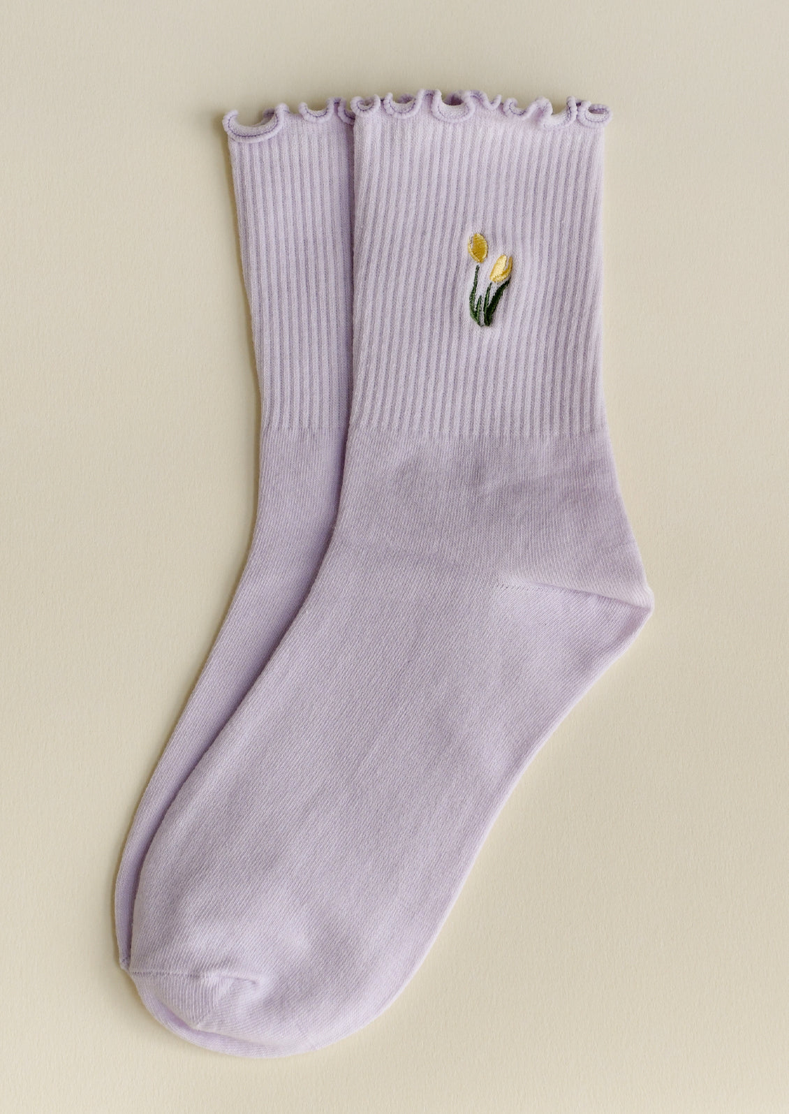 A pair of lilac socks with embroidered tulip motif in butter yellow.