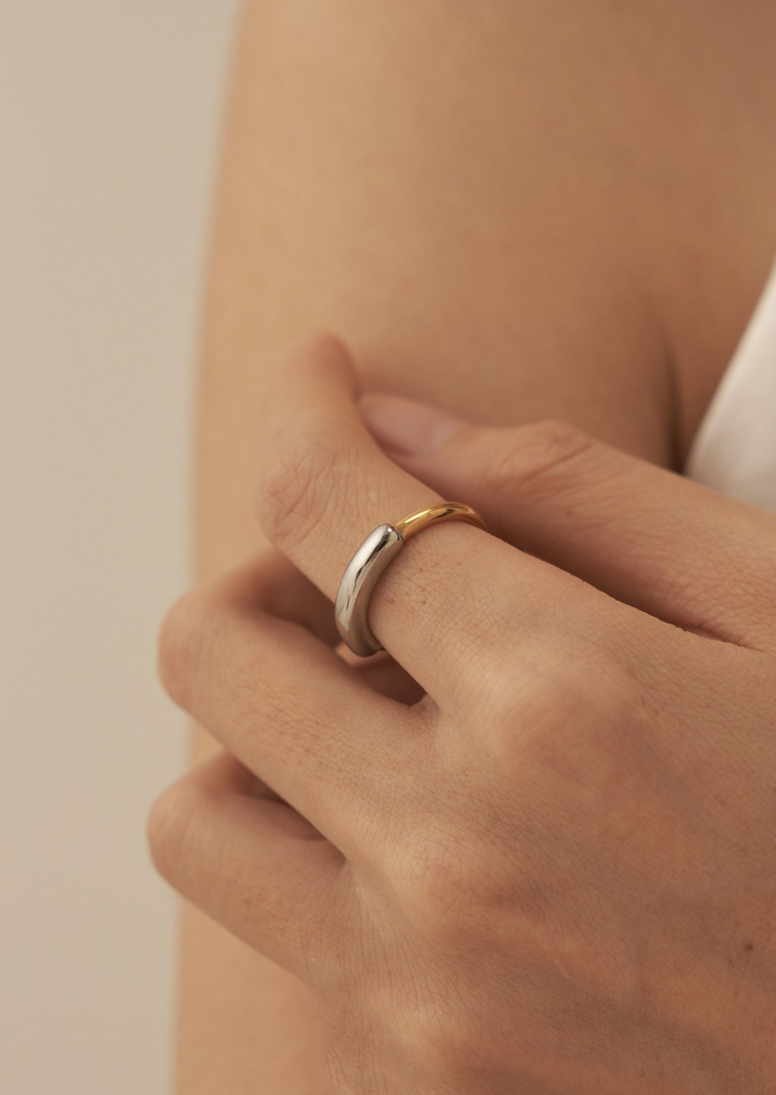 A woman wearing a mixed metal gold and silver ring with asymmetrical band thickness.