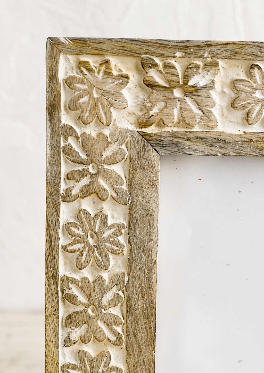 2: A wooden picture frame with carved whitewash floral design.