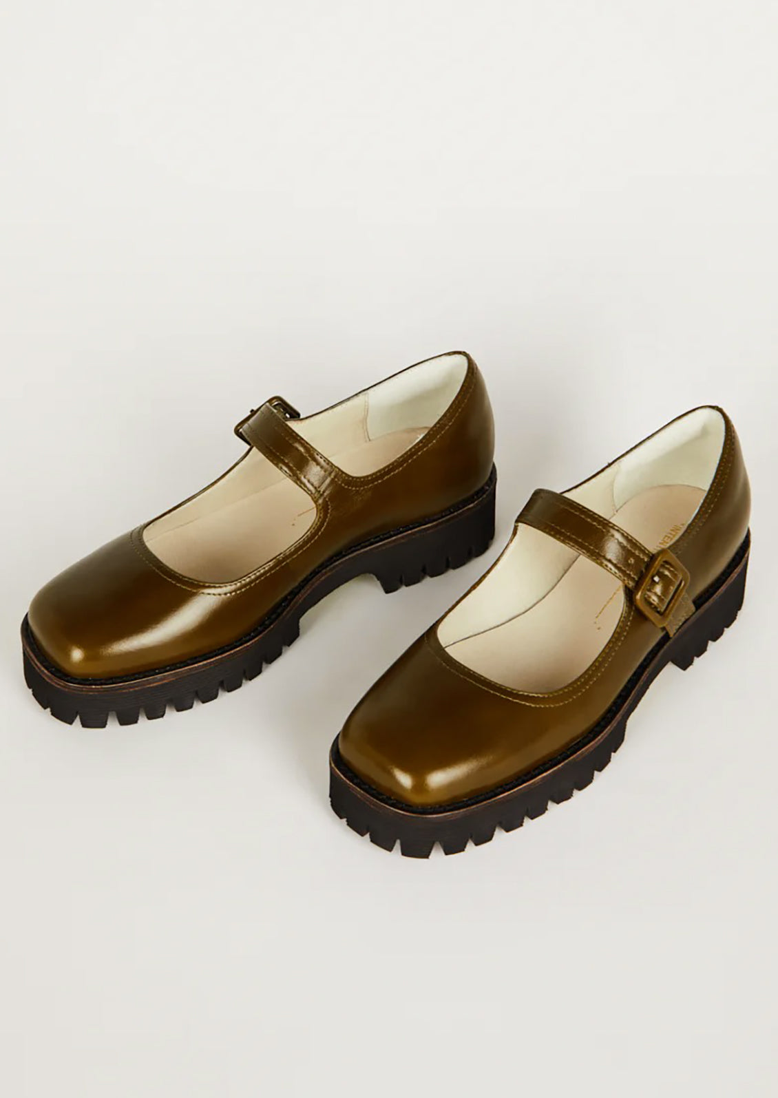 A pair of mary jane shoes in olive green with chunky lug sole.