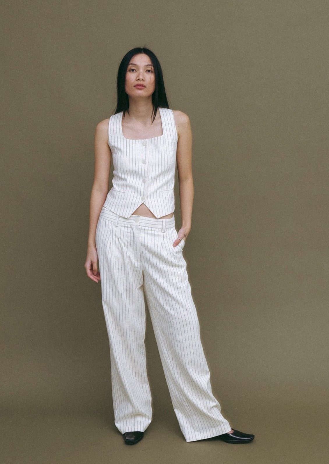 A woman wearing a white baseball style vest with black pinstripe.