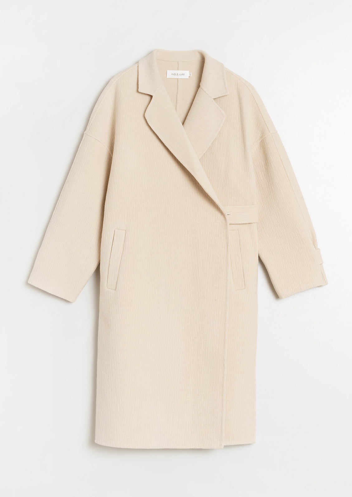 A woman wearing a wool coat with subtle texture and tab closure.