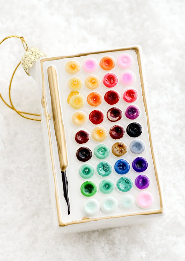 A holiday ornament designed to look like a palette of watercolor paints.