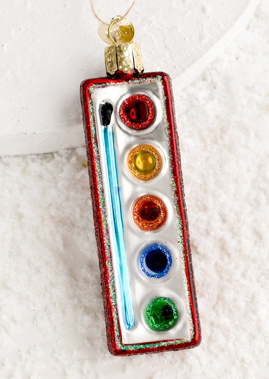A glass holiday ornament of small watercolor pan.