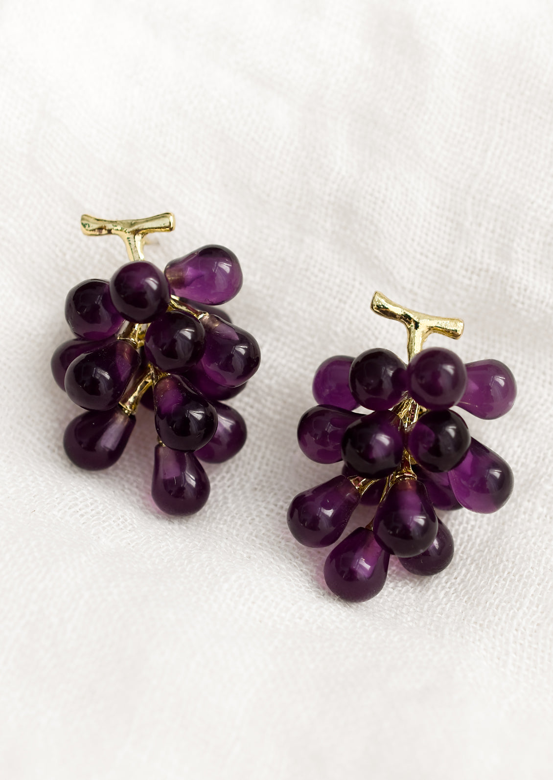 A pair of earrings in the shape of purple grape bunches.