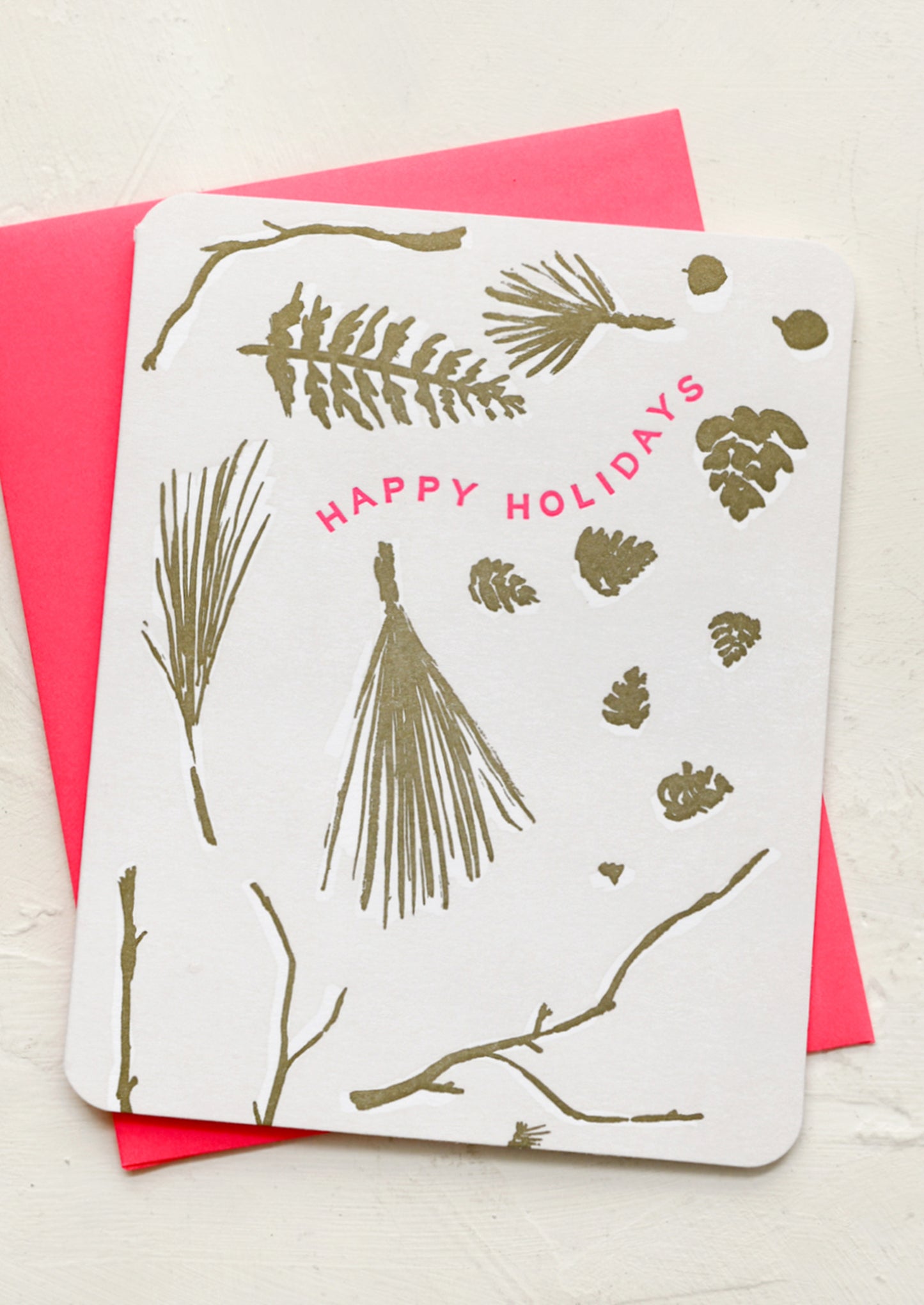 A greeting card with illustration of various winter foliage, neon pink text reads "Happy Holidays".