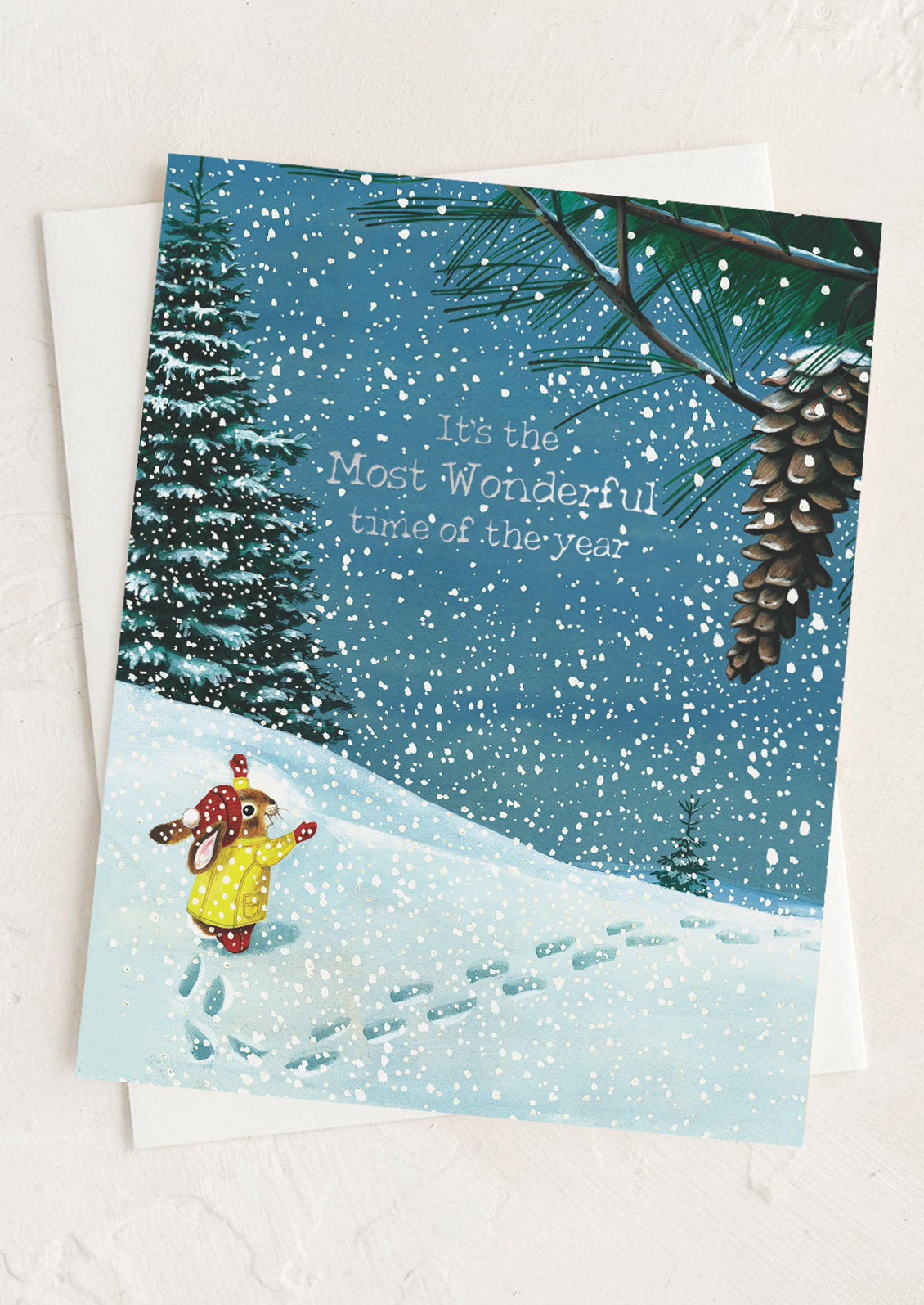 A greeting card with illustration of a rabbit playing in the snow, text reads "It's the most wonderful time of the year".