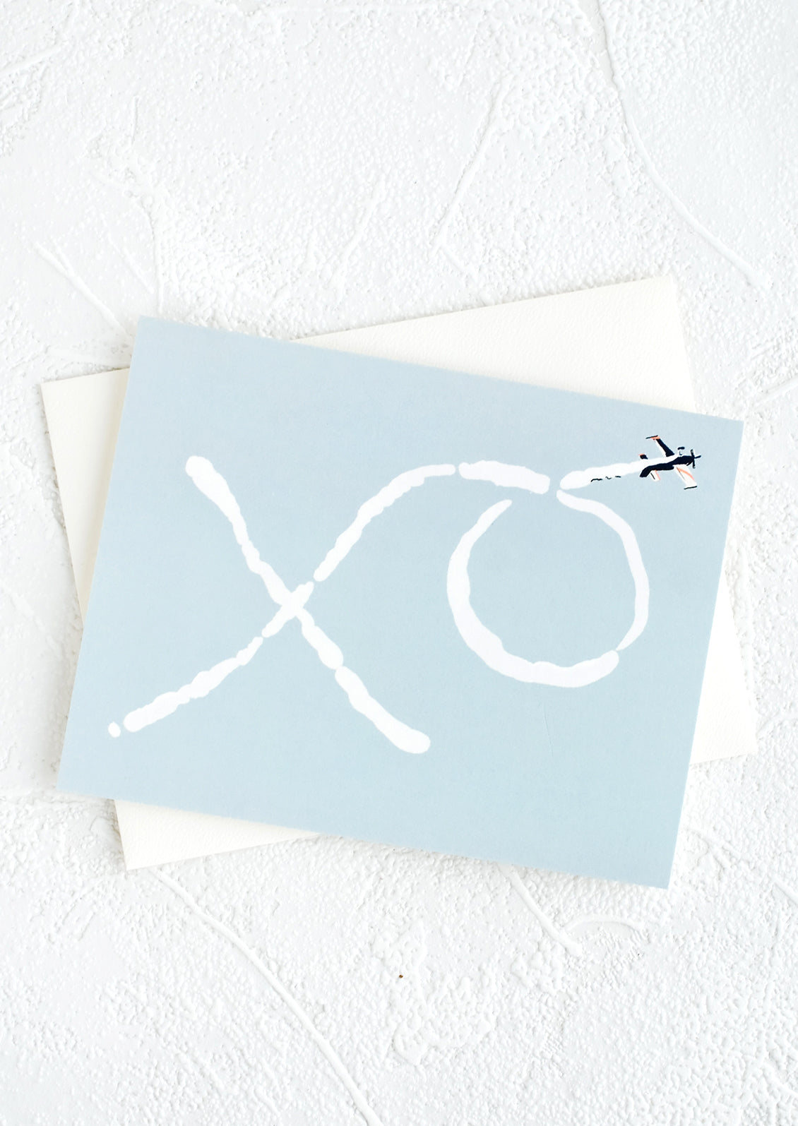 A blue colored greeting card with image of "XO" written by a skywriter plane.