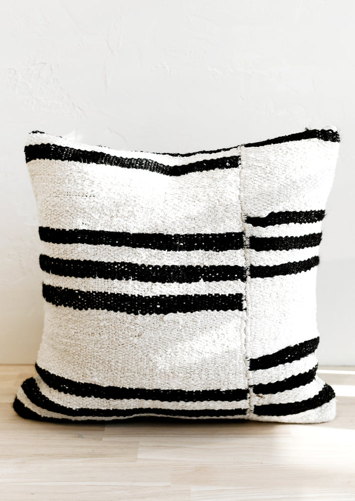 1: A square throw pillow in white hemp with triple black stripes.