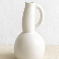 1: A white ceramic pitcher with curved, voluptuous silhouette.