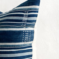 3: Embroidery detailing on a striped indigo fabric pillow.
