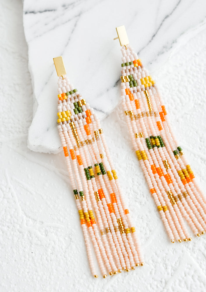 Rosado Multi: Long fringe earrings of pink glass beads with pattern of geometric shapes in green and orange on a small brass post.