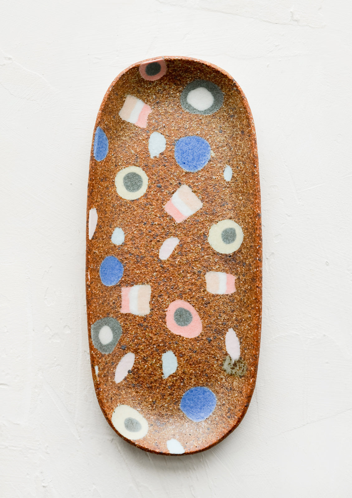 An oblong ceramic catchall tray with various inlay shapes.