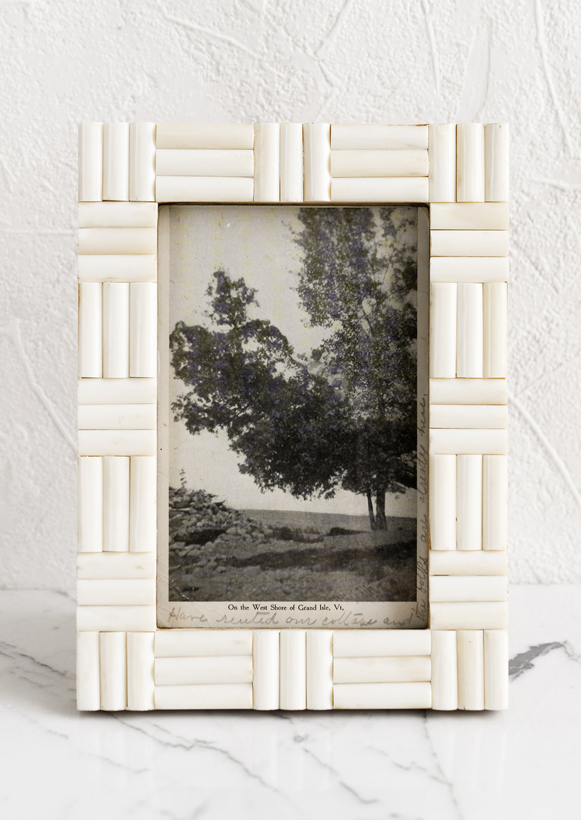 An ivory picture frame with alternating direction inlay.