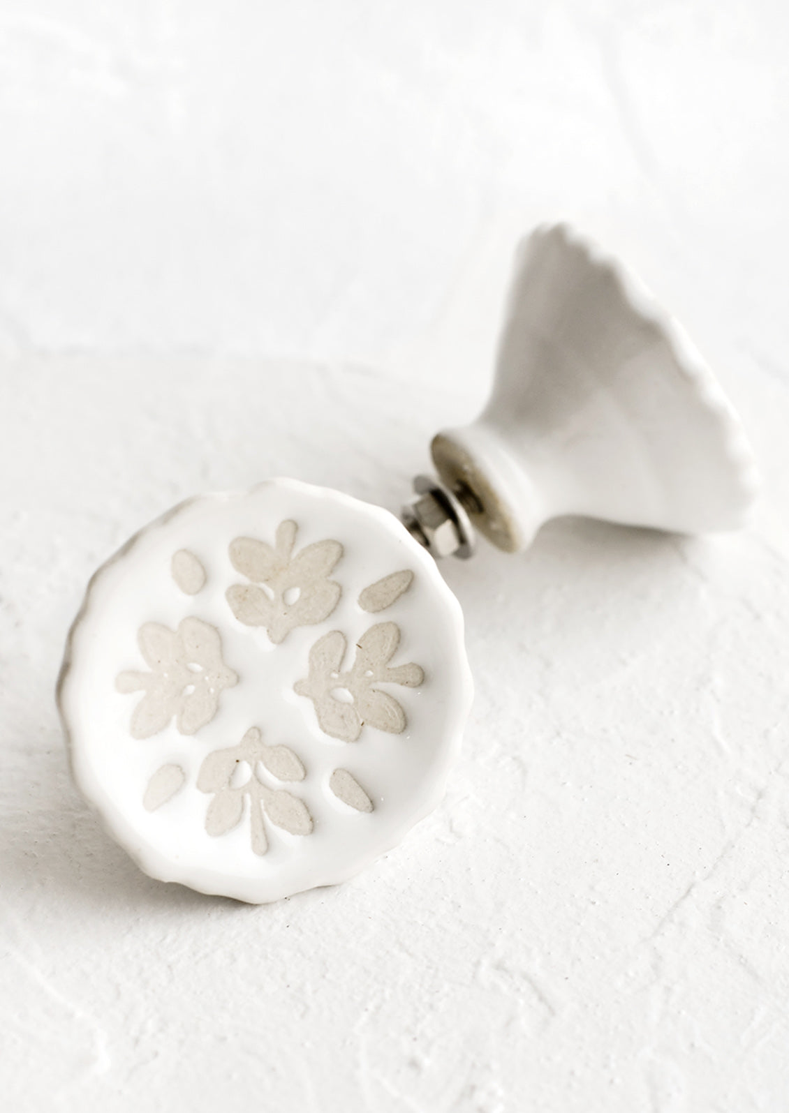 White ceramic cabinet knobs with floral relief pattern.