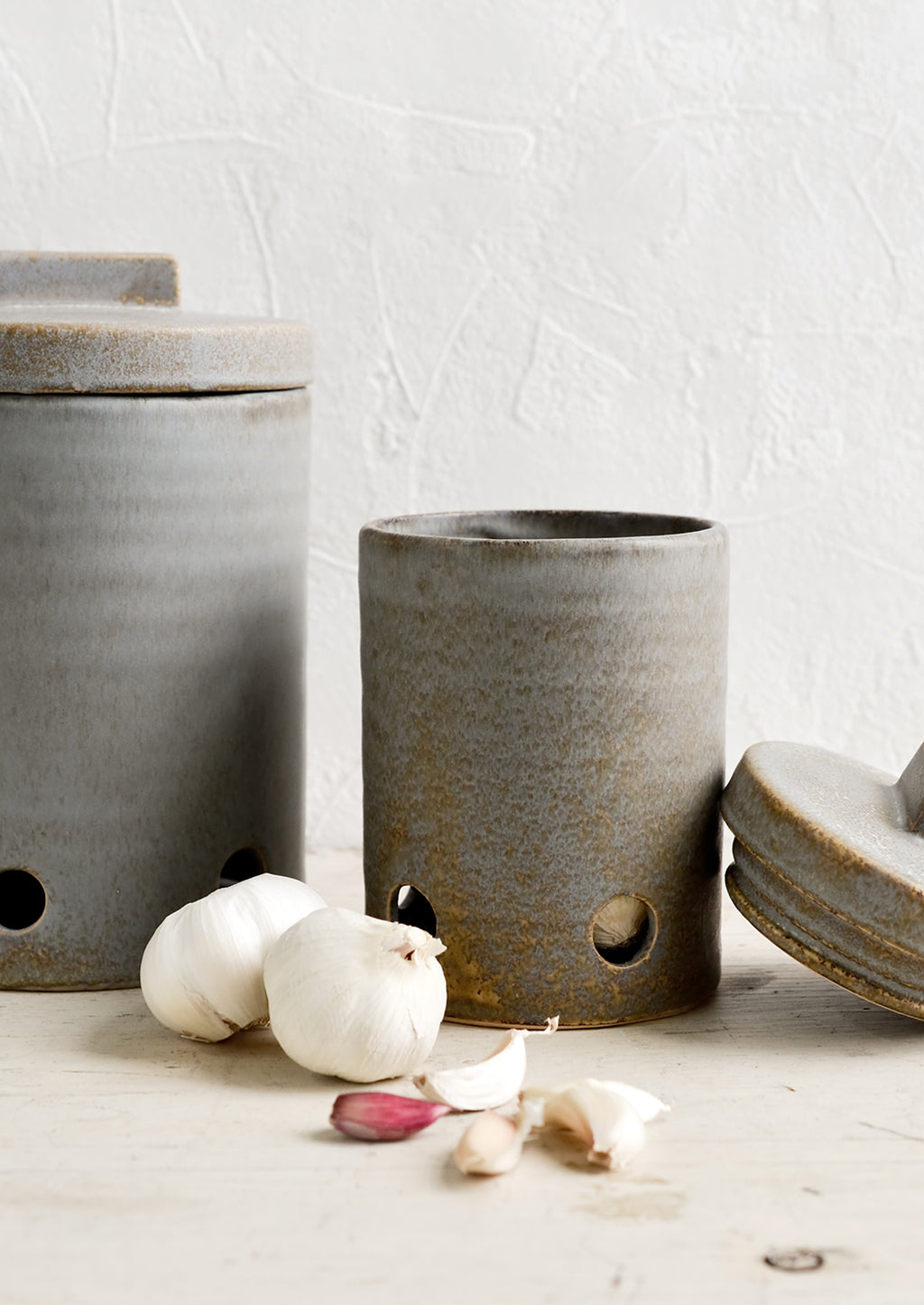 1: Ceramic kitchen storage jars in two sizes intended for onion and garlic storage.