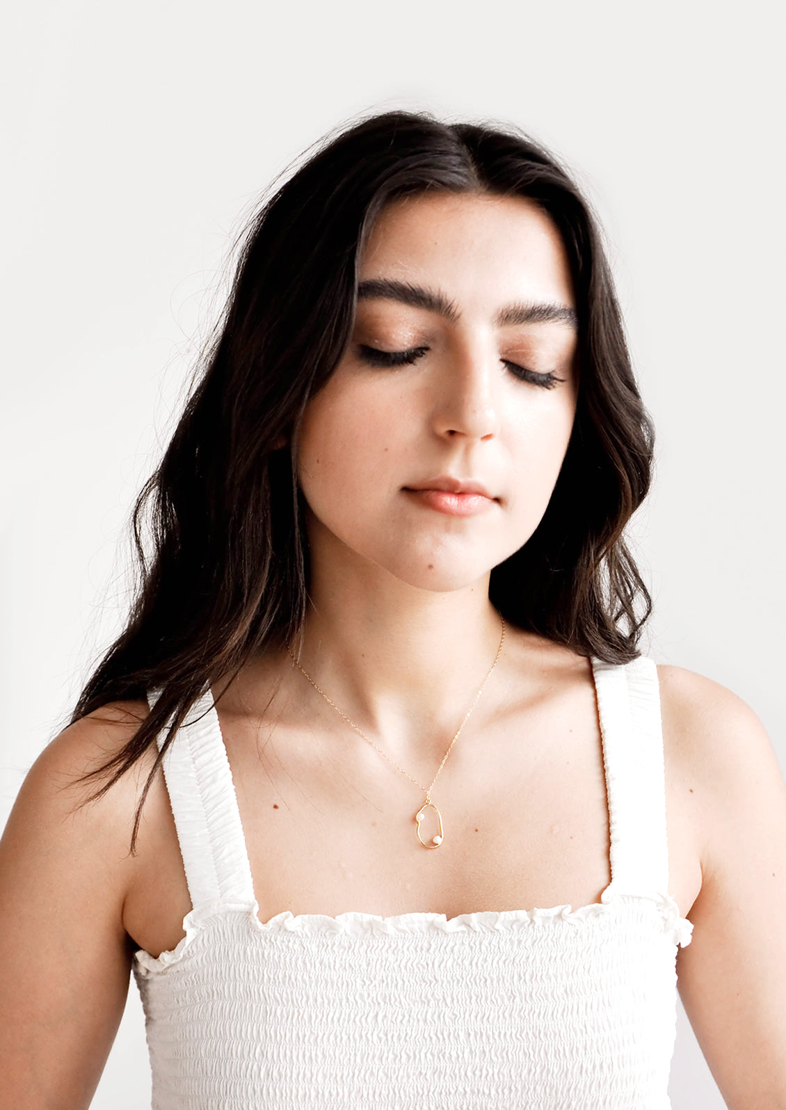 Model shot showing woman wearing necklace and white top.