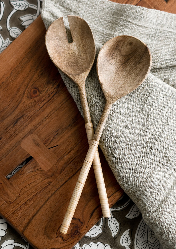 1: A pair of wooden salad servers with rattan wrapped handle.