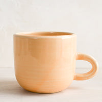 Nectar (Glossy): A short ceramic coffee mug in glossy pastel peach glaze.