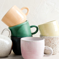 1: A stack of ceramic mugs in a mix of glazes and colors.
