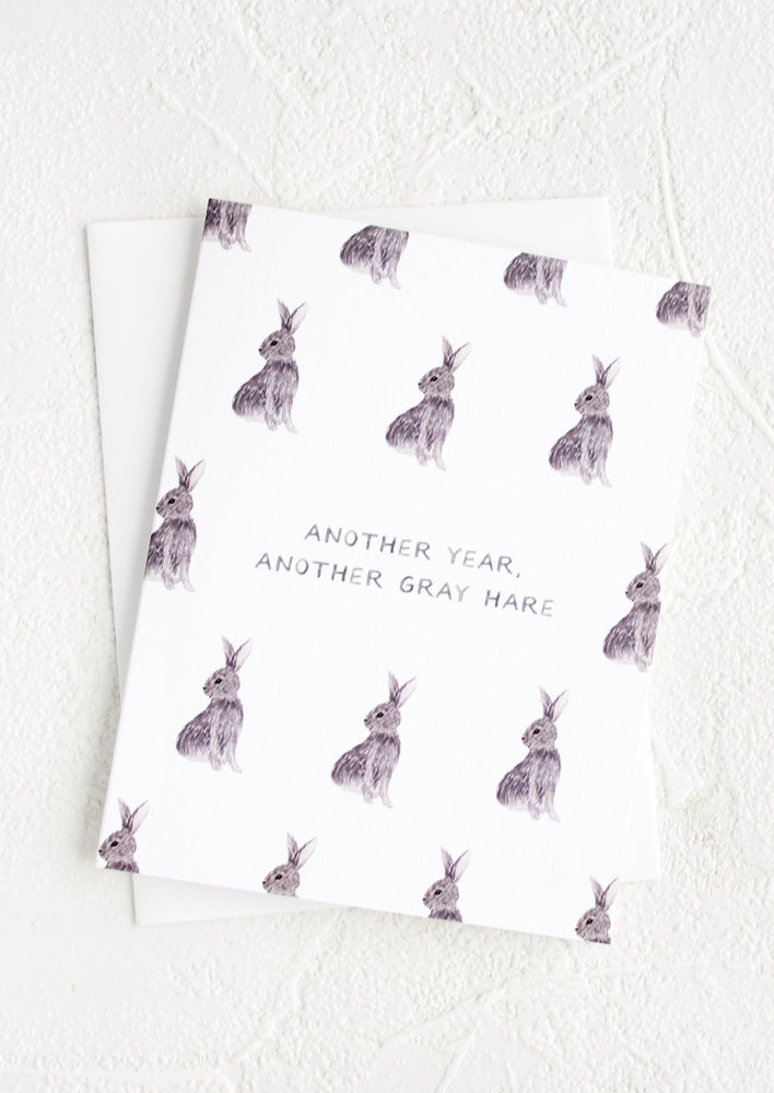 A white greeting card with illustrated grey bunnies and text reading "Another year, another gray hare".