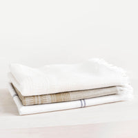 1: Three folded cotton towels stacked neatly in a pile.