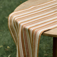 2: A tan striped table runner on a table.