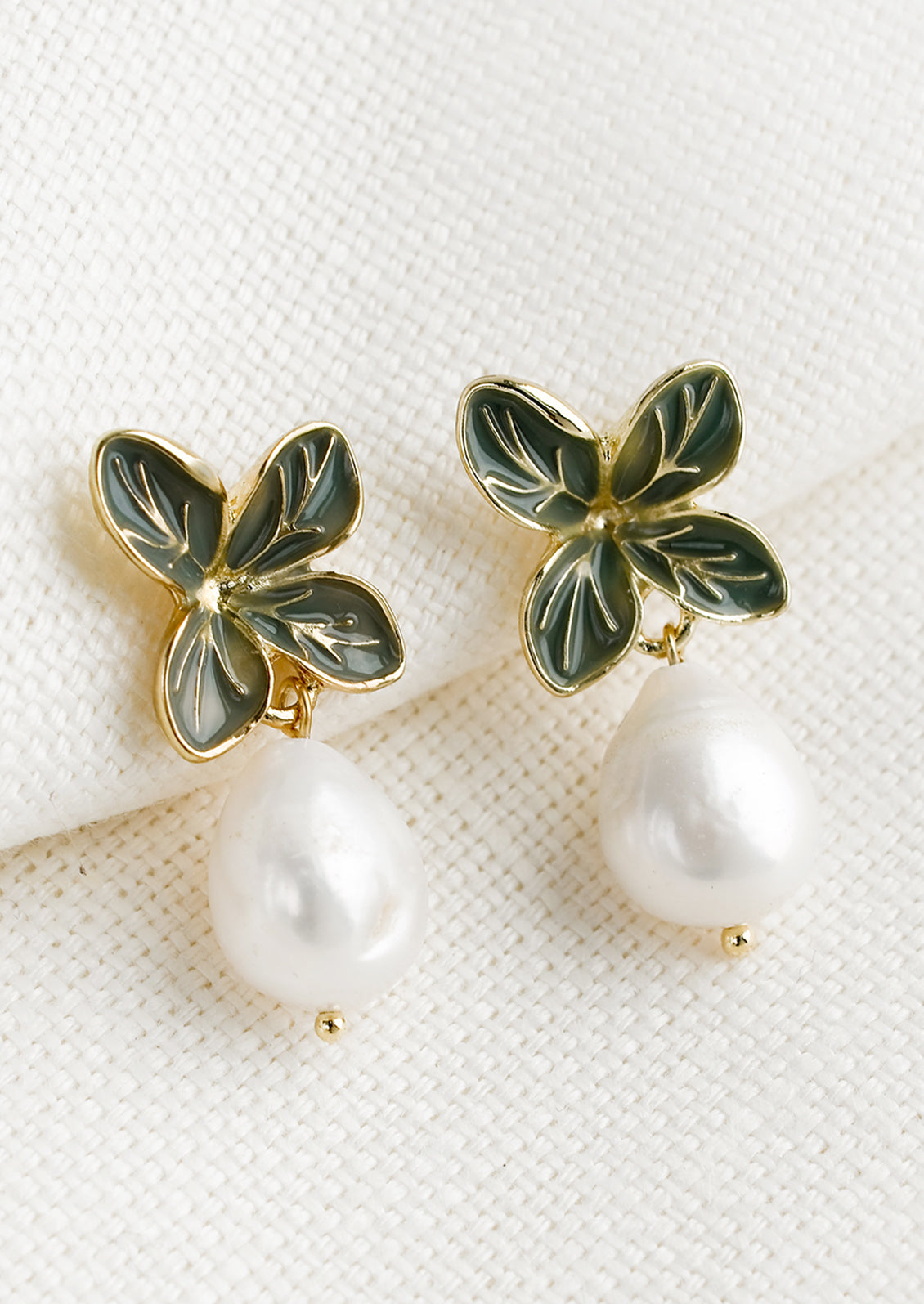 A pair of earrings with four leaf enamel post and pearl.