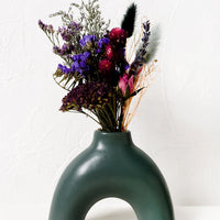 2: A ceramic arch shaped vase with dried flowers.