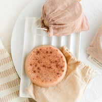 2: A round soap bar with naturally dyed muslin pouches on marble soap dish.