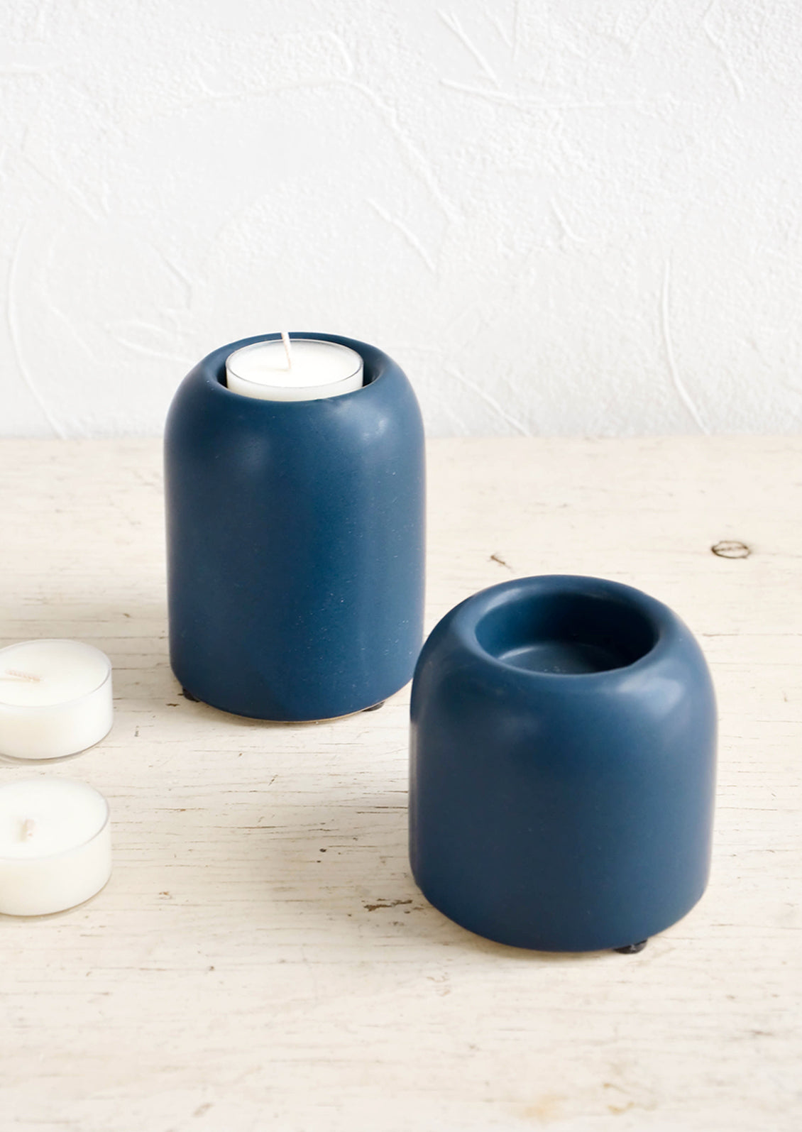 Ceramic tealight holders in jewel-tone blue, shown on table with tealights
