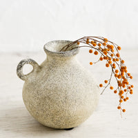 3: A petite ceramic bud vase in tan patina finish, holding dried mimosa sprig.