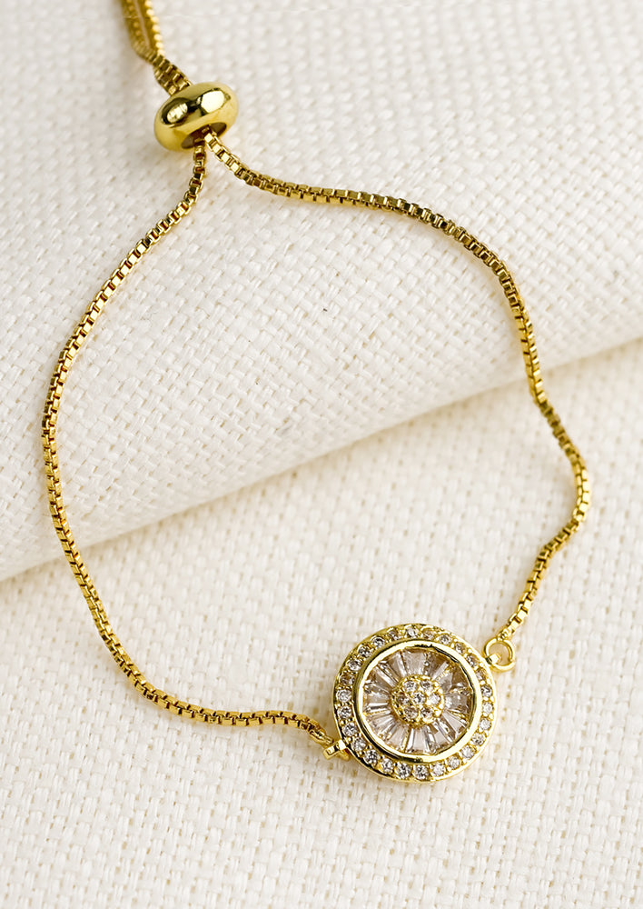 A gold bracelet with round vintage inspired crystal charm.