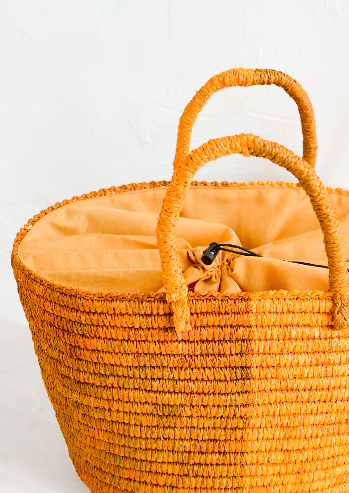 A raffia tote bag with drawstring lining.