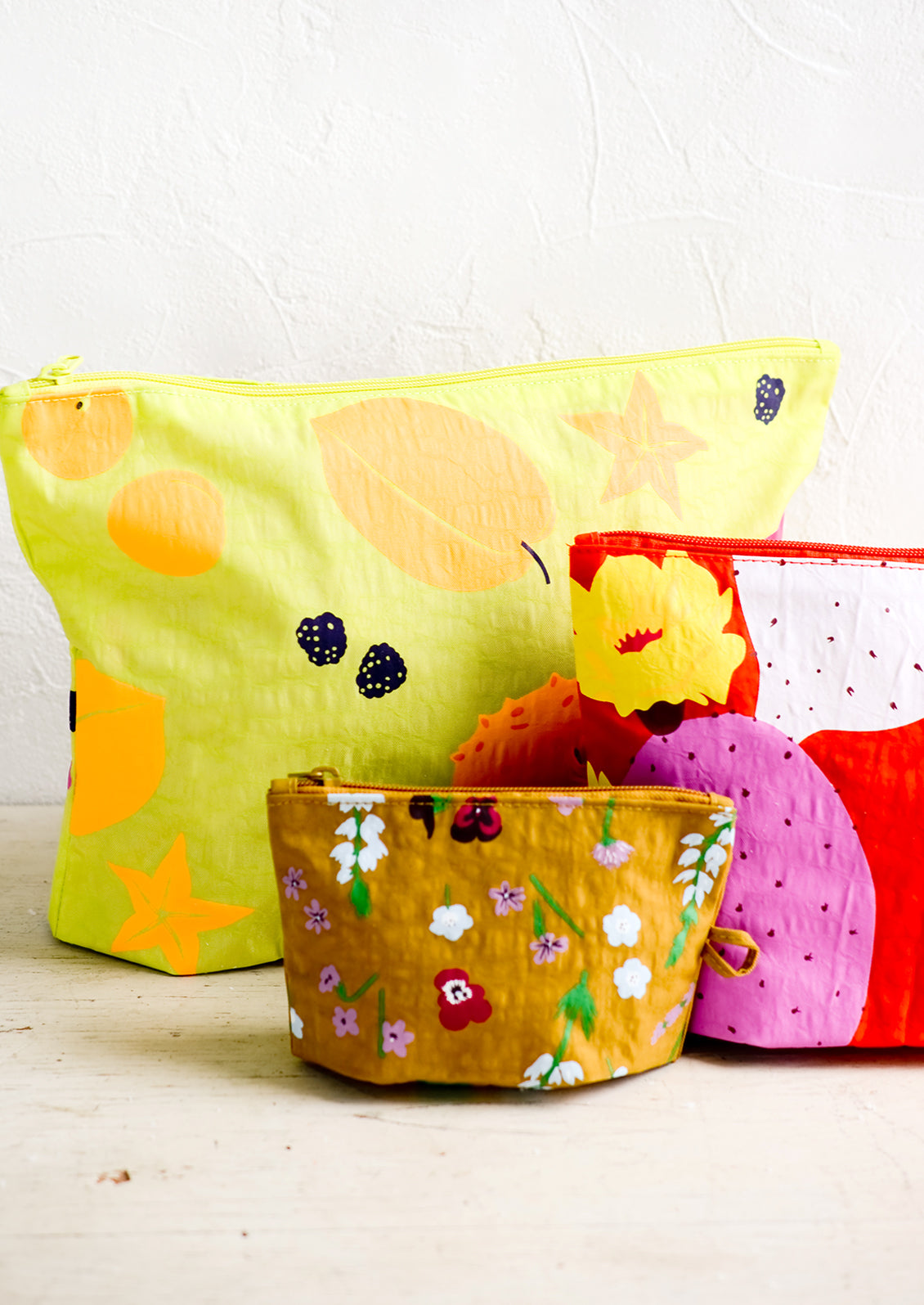 A set of three nylon pouches in different colors and patterns and incremental sizes.