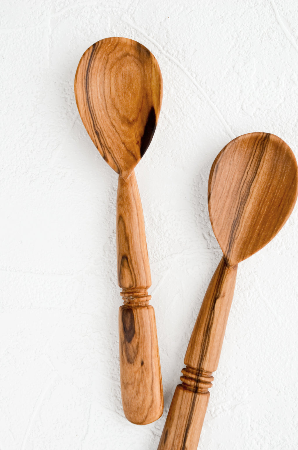 1: Two hand-carved spoons made from olivewood, each with its own unique grain pattern.