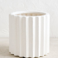 1: A matte white ceramic planter in grooved, geometric shape.