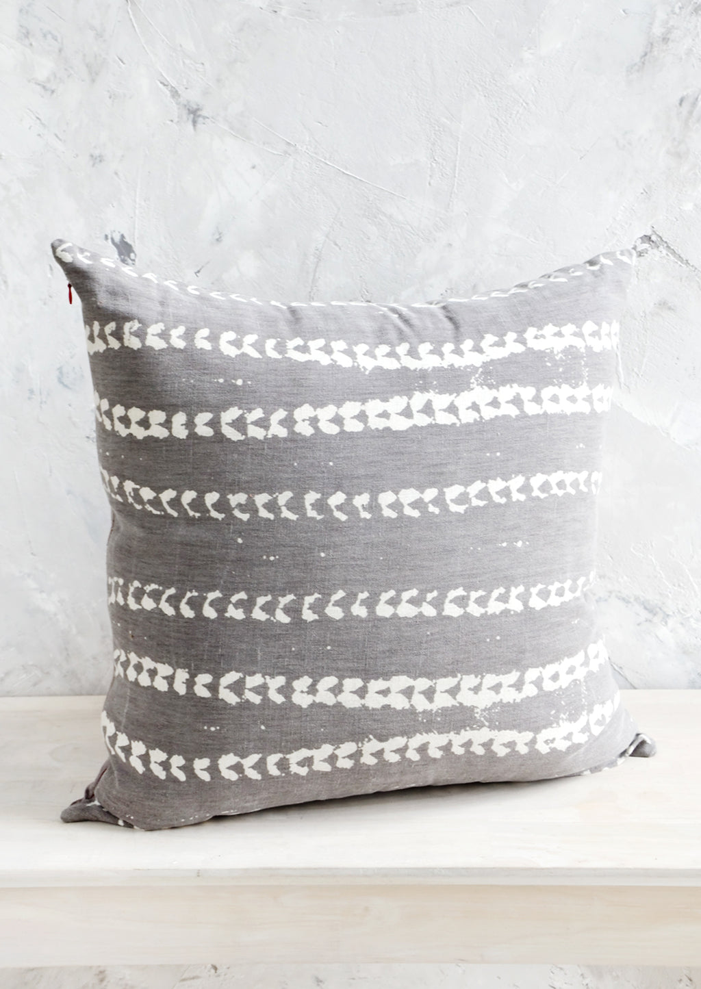 Grey / White: Square throw pillow in grey linen with horizontal batik print stripe pattern in white.