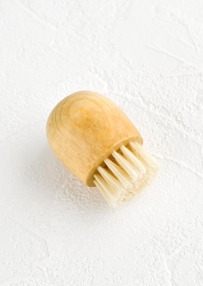 1: A small wood and boar bristle handheld brush with round top.