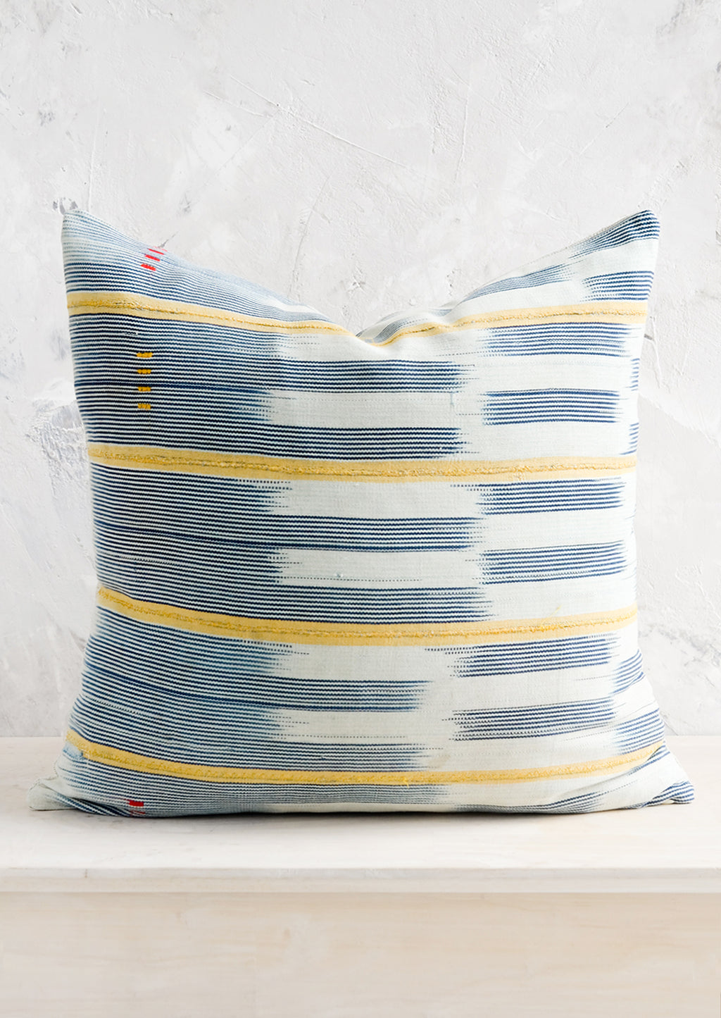 1: A square throw pillow in vintage African baule indigo ikat fabric with yellow accents.