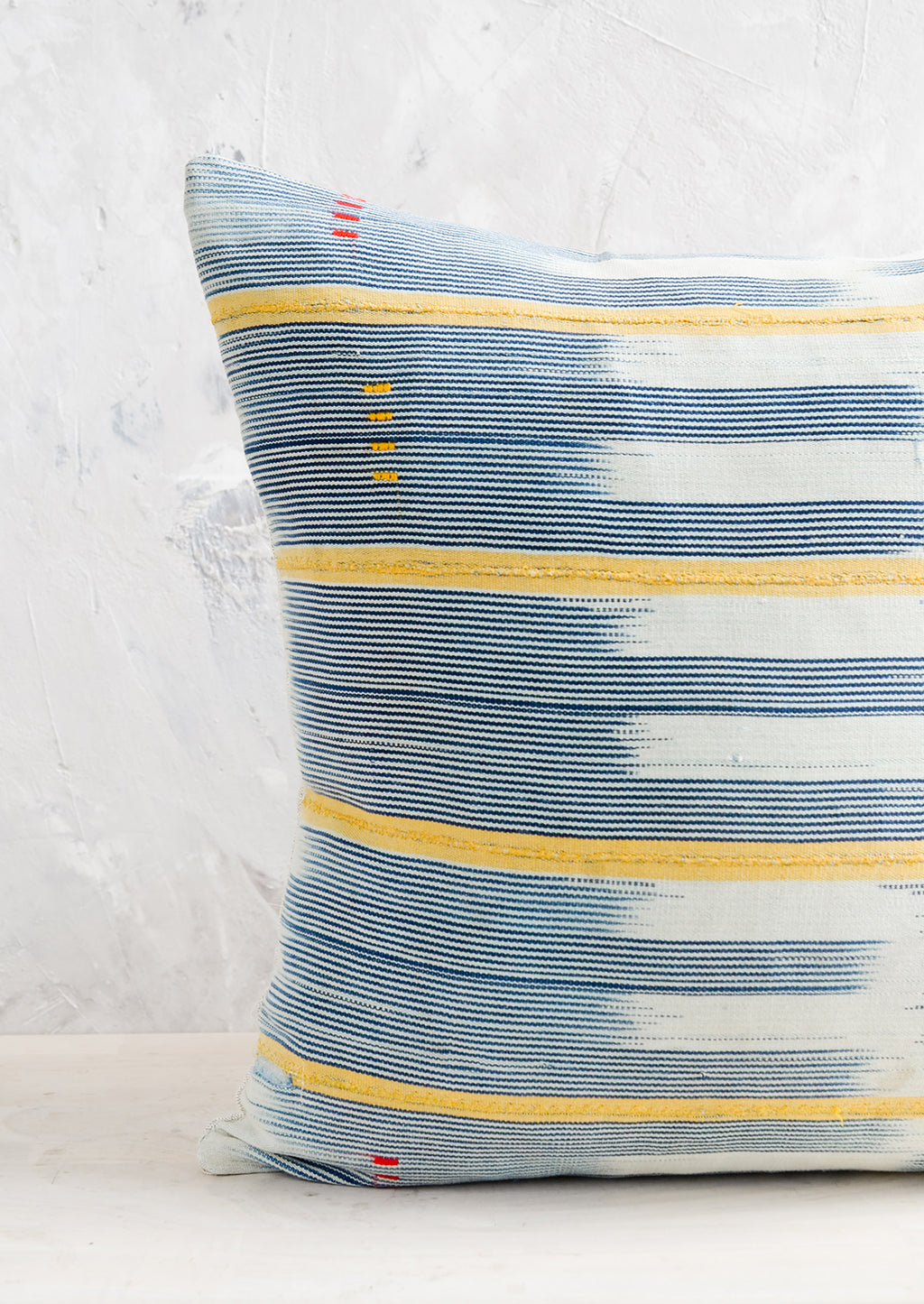 2: A square throw pillow in vintage African baule indigo ikat fabric with yellow accents.